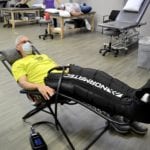 gray haired man reclining in chair with Normatec Compression Boots on his legs