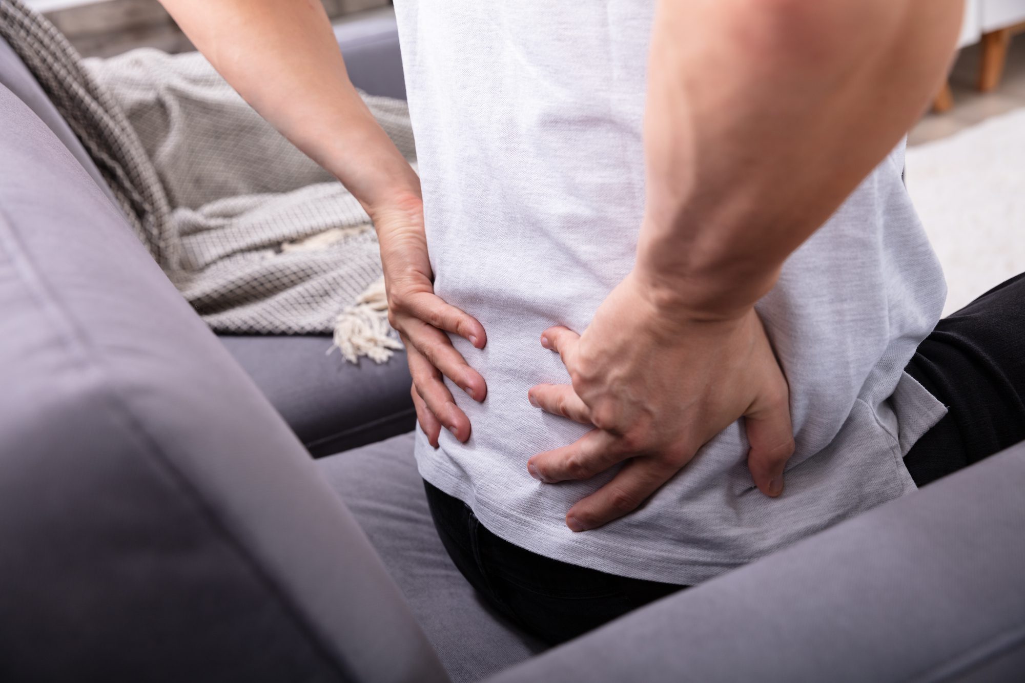 Close-up Of A Man Sitting On Sofa Having Back Pain