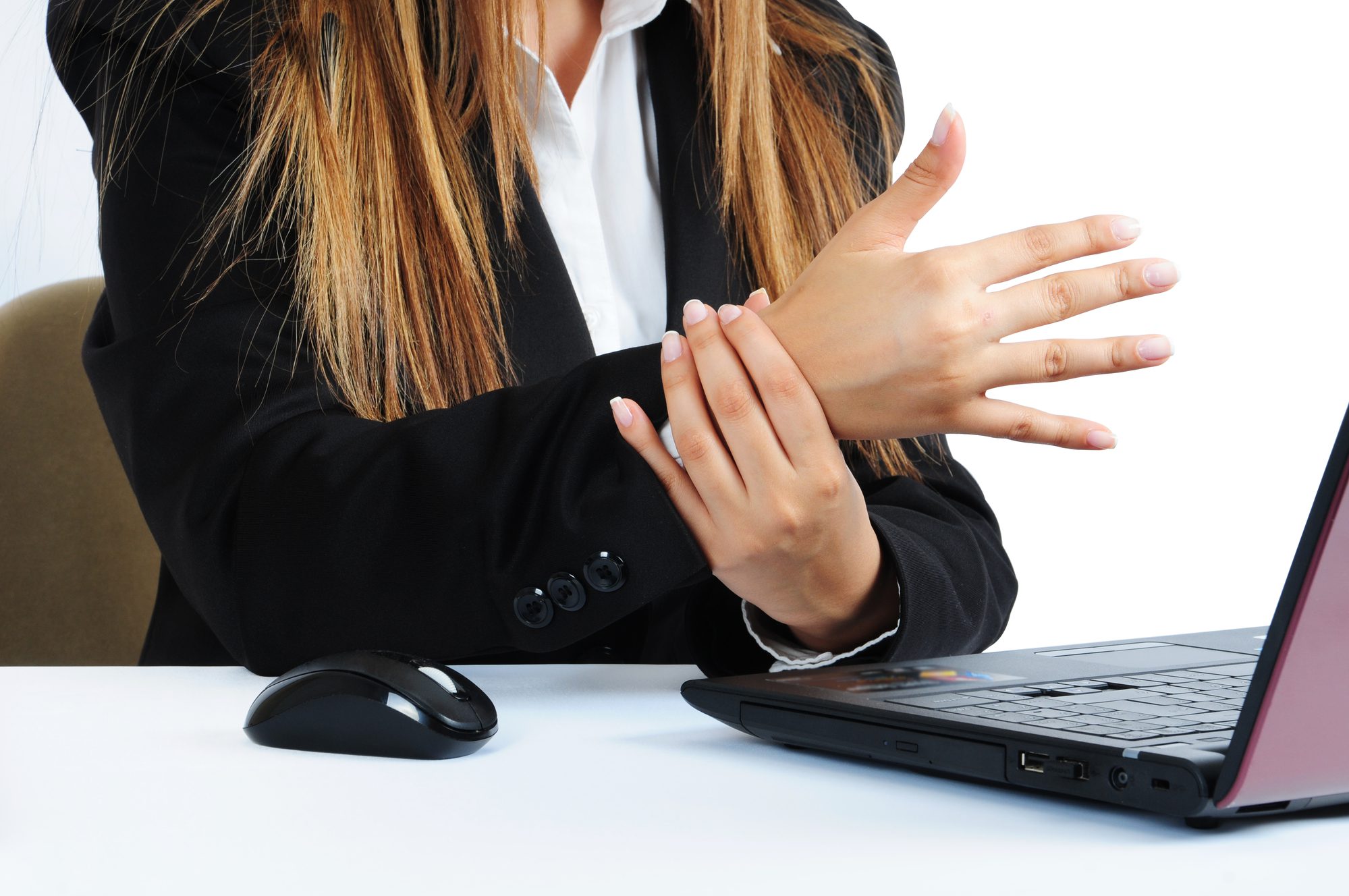 white woman sitting at laptop holding her hand due to carpal tunnel pain